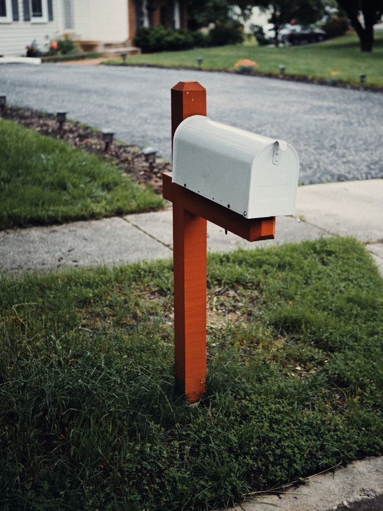 A white mailbox at the end of a driveway