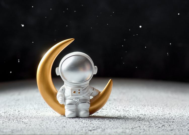 A toy astronaut sitting on a toy moon